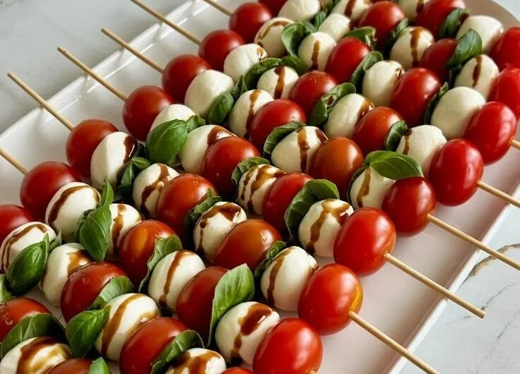 Colorful Caprese Skewers with tomatoes, mozzarella, and basil drizzled in balsamic glaze