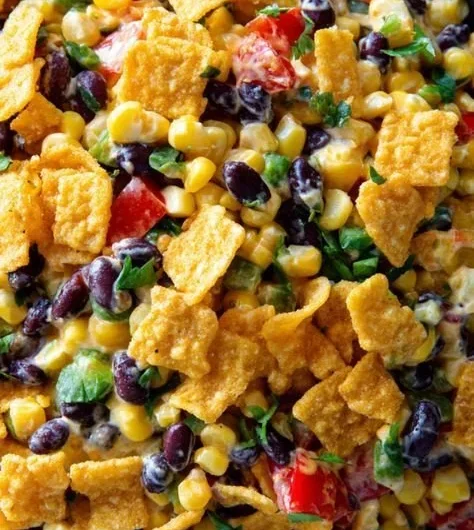 Bowl of creamy Frito Corn Salad garnished with peppers and onions