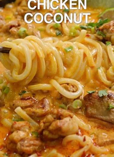 Bowl of Thai coconut red curry chicken udon garnished with fresh herbs