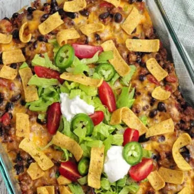 Delicious Walking Taco Casserole topped with cheese, salsa, and crushed chips