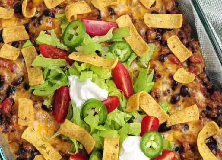 Delicious Walking Taco Casserole topped with cheese, salsa, and crushed chips