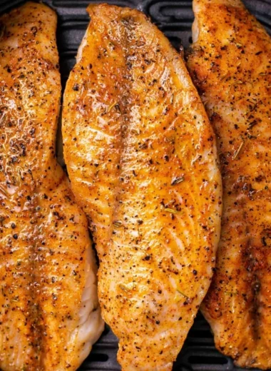 Crispy air fryer tilapia served on a plate with lemon and herbs.