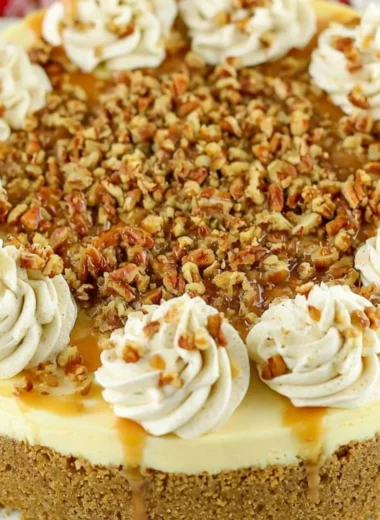 Slice of Browned Butter Pecan Cheesecake on a plate with pecans on top