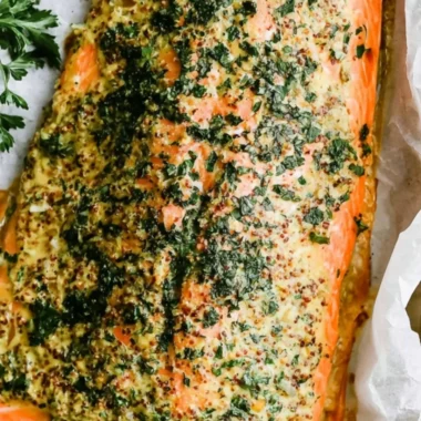 Dijon baked salmon fillet served with lemon and herbs on a plate