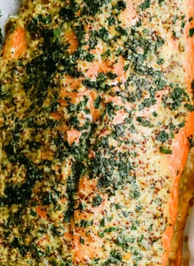 Dijon baked salmon fillet served with lemon and herbs on a plate