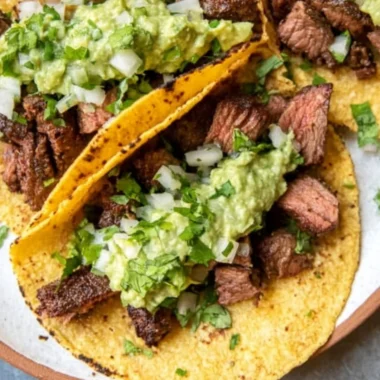 Grilled steak tacos served with avocado salsa in a vibrant setting