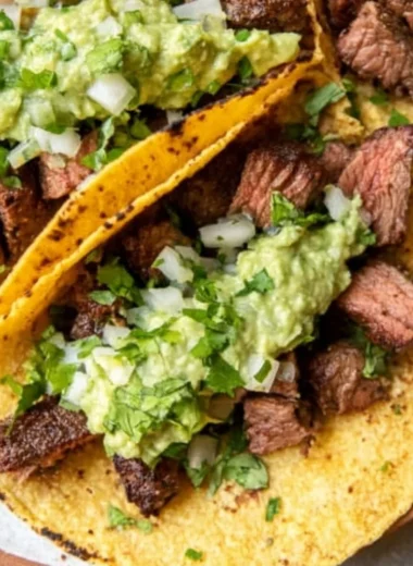Grilled steak tacos served with avocado salsa in a vibrant setting