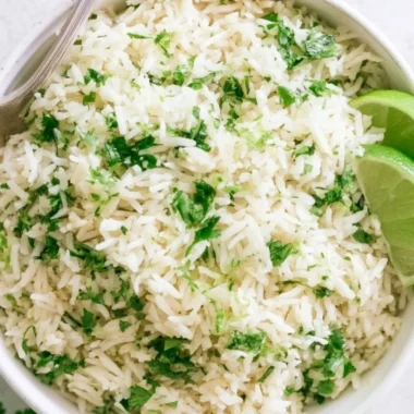 Bowl of homemade cilantro lime rice with fresh cilantro and lime wedges