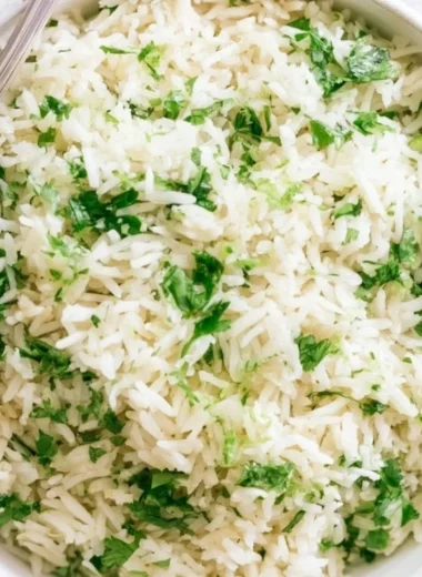 Bowl of homemade cilantro lime rice with fresh cilantro and lime wedges