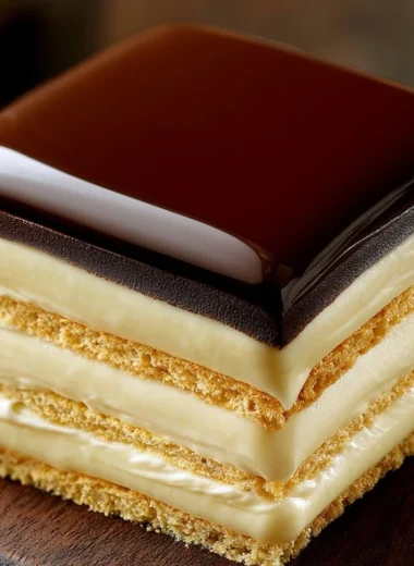 No-bake chocolate eclair cake topped with chocolate glaze and cream filling