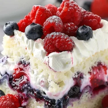 Delicious Summer Berry Poke Cake topped with fresh berries and whipped cream
