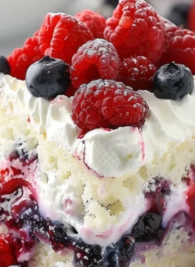 Delicious Summer Berry Poke Cake topped with fresh berries and whipped cream