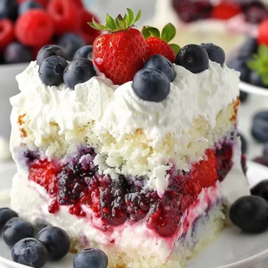 A delicious Summer Berry Poke Cake topped with fresh berries and cream.
