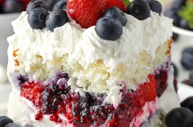 A delicious Summer Berry Poke Cake topped with fresh berries and cream.