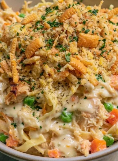 Homemade chicken noodle casserole served in a dish with fresh herbs on top.