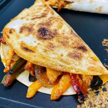 Cozy Blackstone chicken fajita quesadillas served on a plate with toppings.