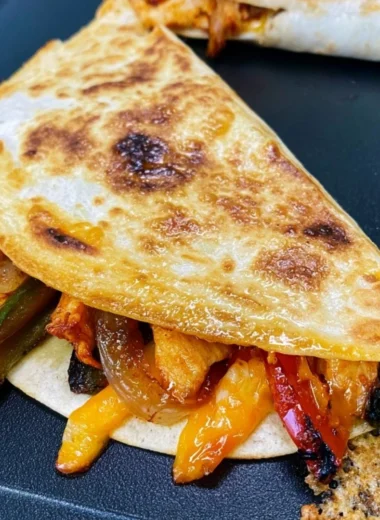 Cozy Blackstone chicken fajita quesadillas served on a plate with toppings.