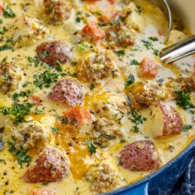 Creamy sausage potato soup served in a bowl with fresh herbs