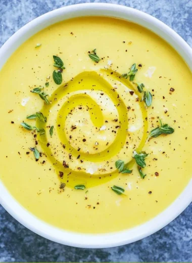 Creamy summer squash soup served in a bowl with fresh herbs on top