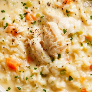 Bowl of creamy chicken rice soup topped with herbs and spices
