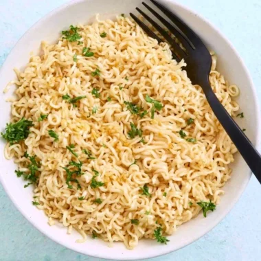 Bowl of garlic butter ramen noodles garnished with scallions and sesame seeds