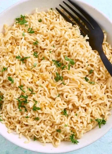 Bowl of garlic butter ramen noodles garnished with scallions and sesame seeds