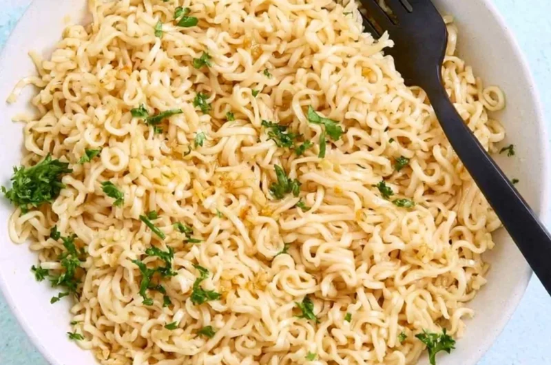 Bowl of garlic butter ramen noodles garnished with scallions and sesame seeds