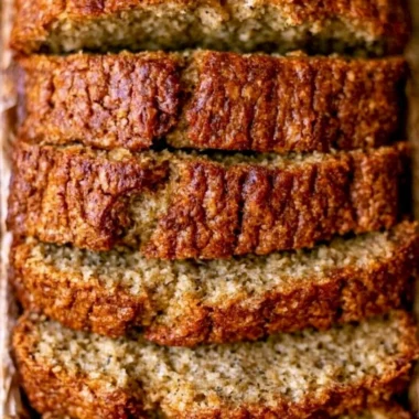 Slice of moist banana bread made with sour cream, served on a wooden board