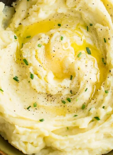 Bowl of perfect creamy mashed potatoes garnished with herbs