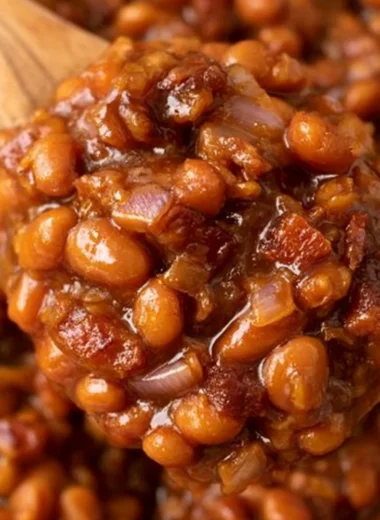 Delicious ultimate baked beans in a rustic bowl next to ingredients