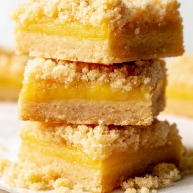 Cozy lemon curd bars on a white plate, garnished with lemon zest.