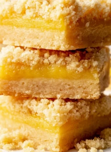 Cozy lemon curd bars on a white plate, garnished with lemon zest.