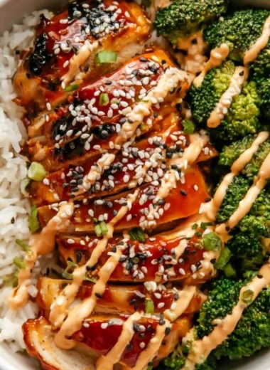 Healthy sticky chicken bowls topped with fresh vegetables and delicious sauce